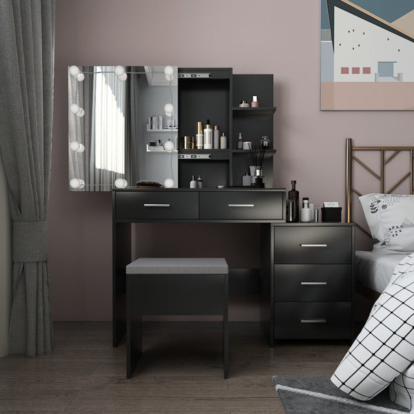 A black dressing table set with a mirror, drawers, and a stool, placed in a bedroom setting.