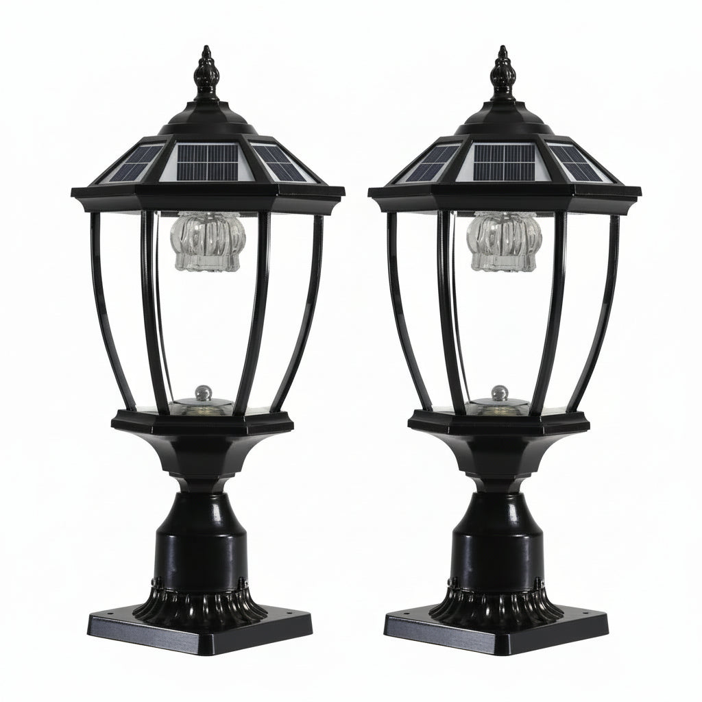 Two black solar-powered LED pillar headlights mounted on outdoor pillars at night, providing a warm white glow.