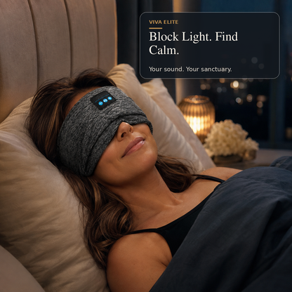 A woman lies in bed wearing a gray sleep mask with illuminated blue LED lights. The scene is dimly lit with pillows, a blanket, and a glowing lamp in the background.