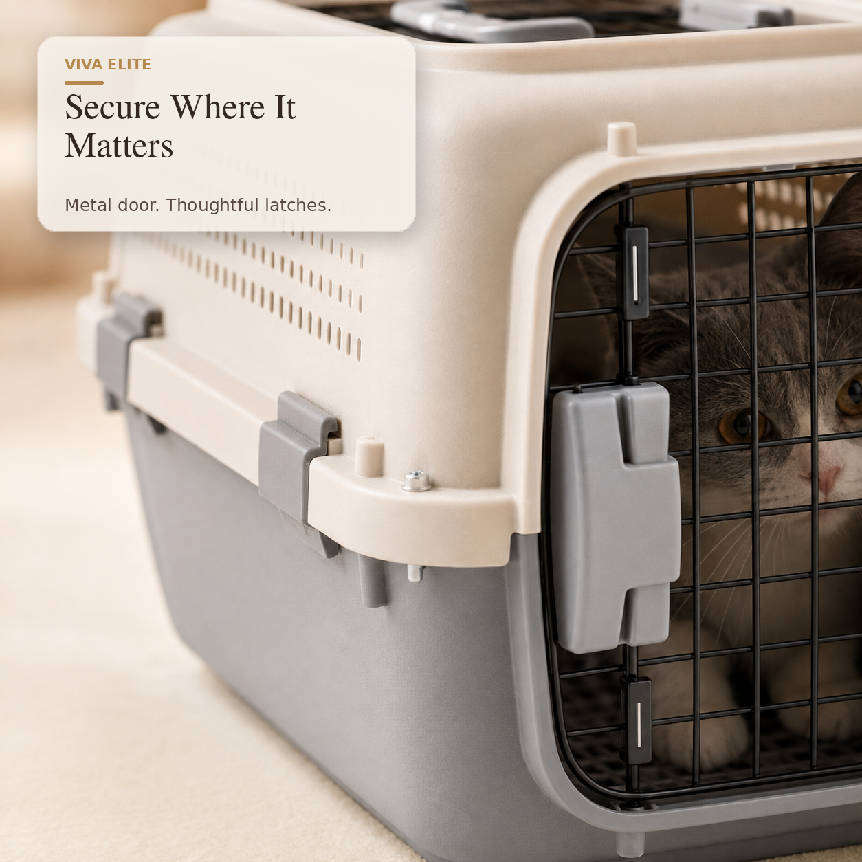 A close-up of a pet carrier with a gray and beige plastic body, a black wire door, and a cat visible inside. A text overlay reads 'VIVA ELITE Secure Where It Matters.