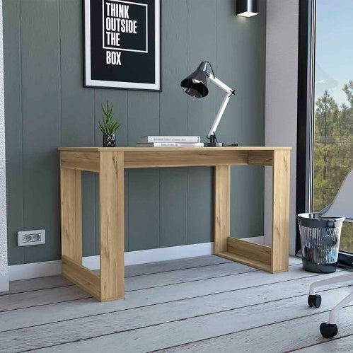 A minimalist Albion computer desk with light oak veneer work surface and black powder-coated steel legs, pictured in a modern room setting with various decorative items on and around it.