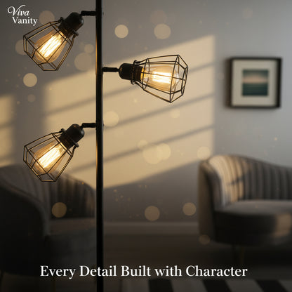 Modern floor lamp with three glass shades in a living room setting with two gray armchairs and a framed picture on the wall.