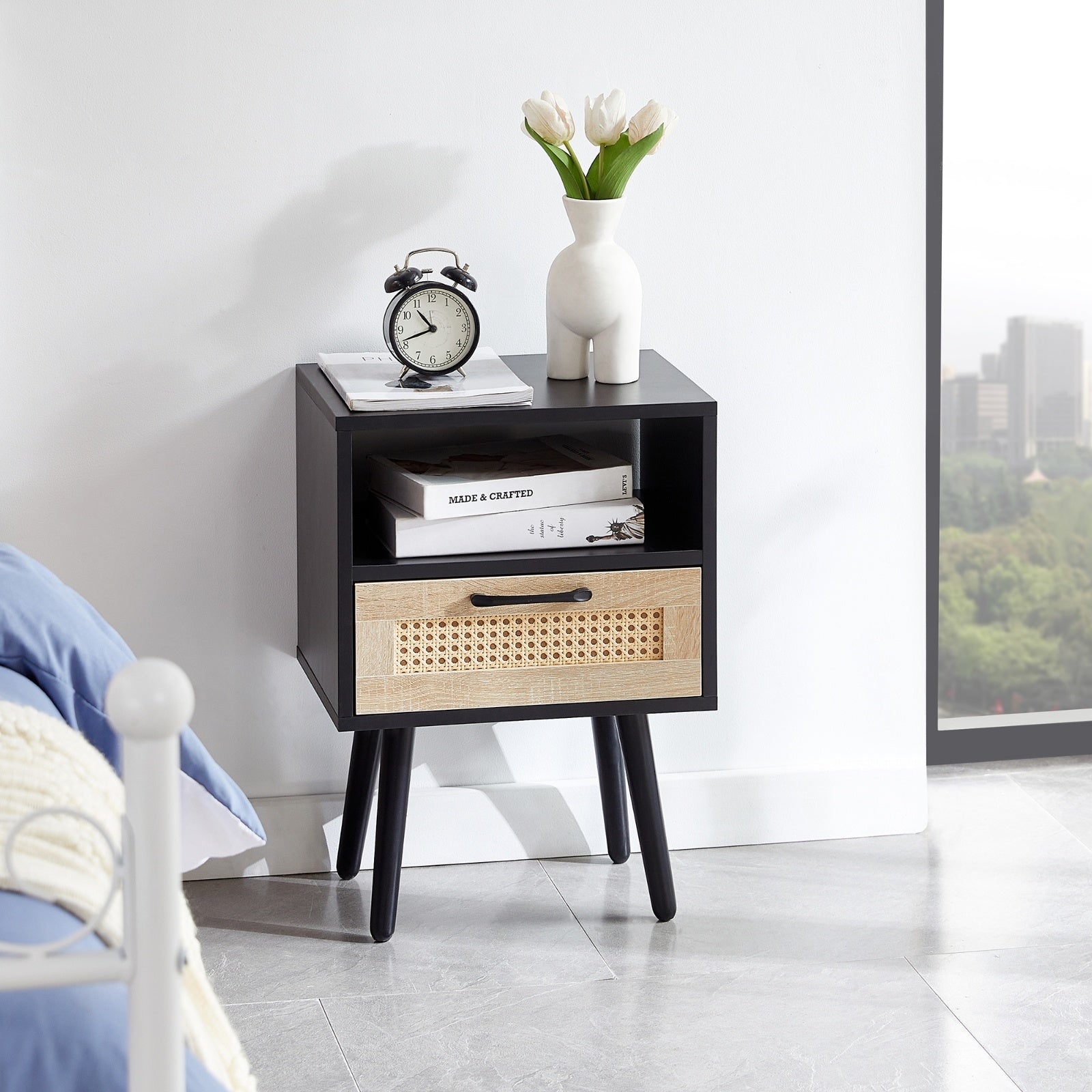 Black nightstand with a wooden drawer in a room with a cityscape view.
