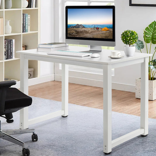 A modern white computer desk with a metal frame and engineered wood top, fitted with a monitor, keyboard, and a coffee cup, set in a room with bookshelves and a plant.