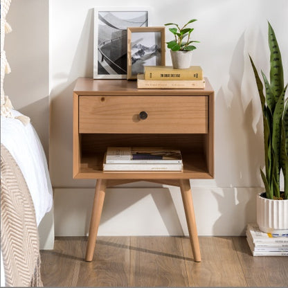 Wooden nightstand with books and a plant in a bedroom setting
