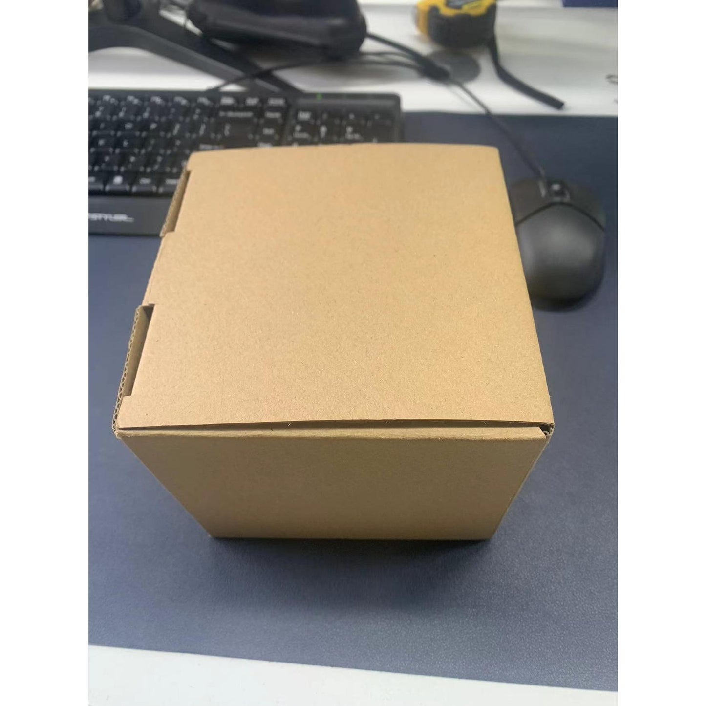 Brown cardboard box on a desk with a keyboard and mouse in the background