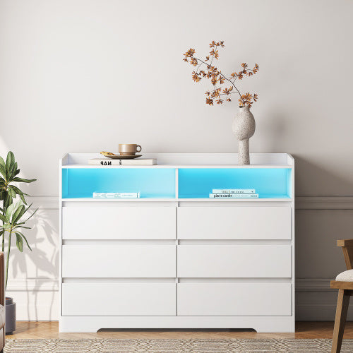 A white vanity with LED lights in a room, featuring multiple drawers and a blue-colored top section.