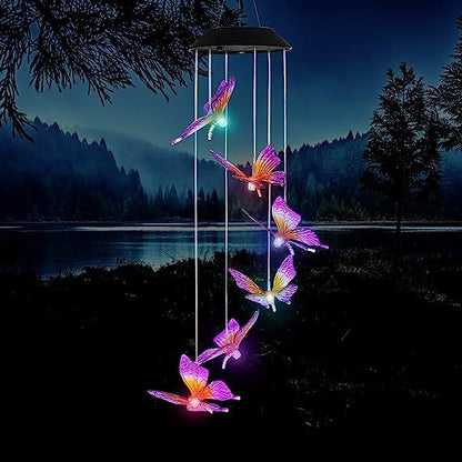 Butterfly-shaped solar light hanging against a night sky with a lake and trees in the background.