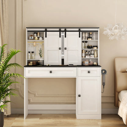 A white farmhouse-style dressing table with a mirror, drawers, and a shelf, equipped with a hair dryer holder and soft-close mechanisms, placed in a room with a plant and a chair in the background.