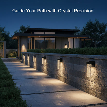 Outdoor pathway with wall-mounted lights leading to a house at night.