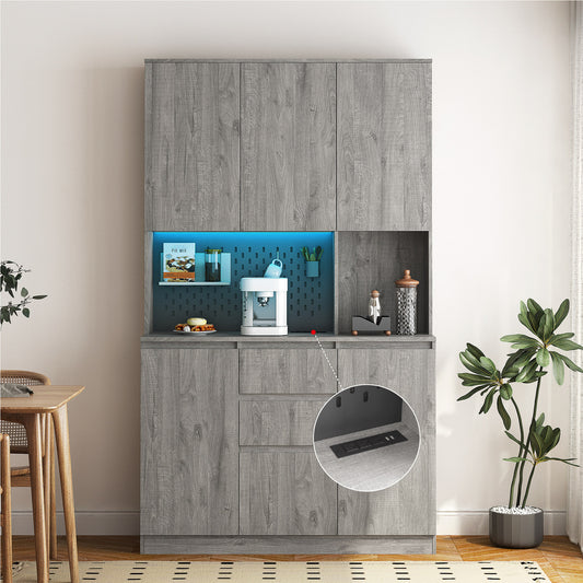 A modern kitchen pantry cabinet with a charging station, LED lighting, and white and gold accents. The cabinet has a closed section, a microwave stand on the top, and an open shelf with items displayed.