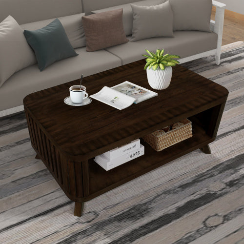 Rectangular wooden coffee table with storage shelf, placed on a wood floor with a sofa, cushions, a cup, plant, and a remote on top.