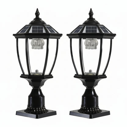 Two black solar-powered LED pillar headlights mounted on outdoor pillars at night, providing a warm white glow.