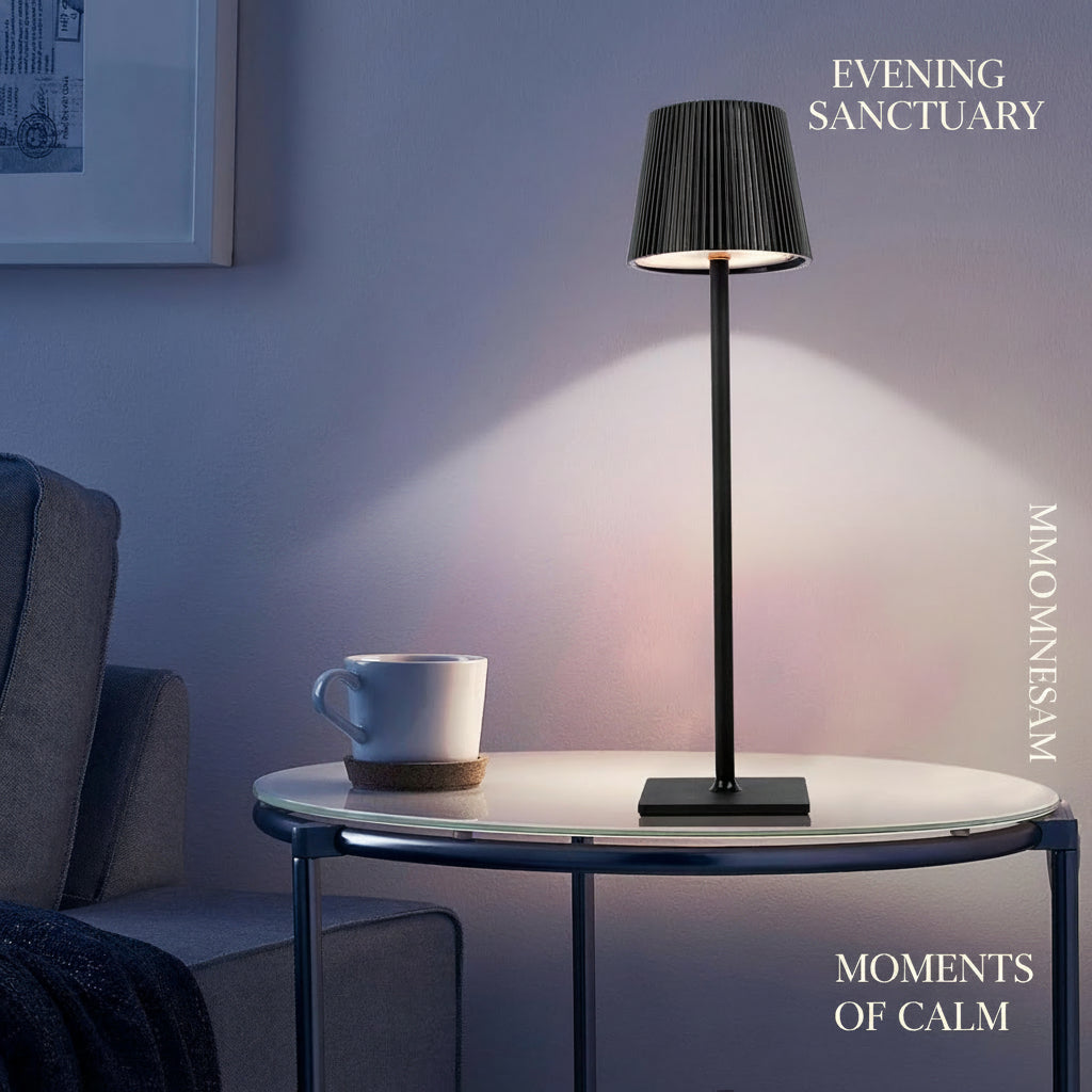 Black table lamp on a round glass table with a white mug, in a room setting.