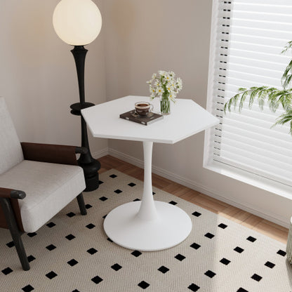 A modern hexagonal white coffee table with a metal base, placed on a checkered patterned rug. The table has a round tray on it, with a floral arrangement and a cup, next to a lamp with a round shade.