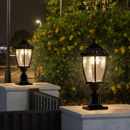 Two black solar-powered LED pillar headlights mounted on outdoor pillars at night, providing a warm white glow.