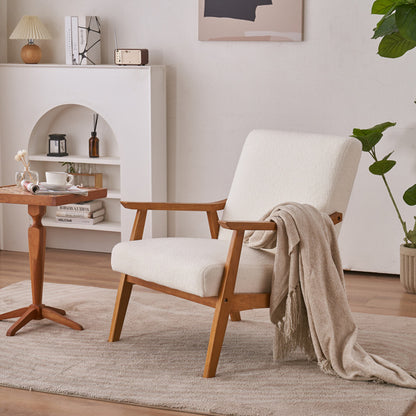 An off-white teddy velvet lounge chair with solid ash wood armrests and a minimalist silhouette, placed in a well-lit living room setting with a side table and a plant in the background.