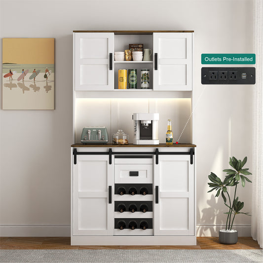A white bar cabinet with sliding barn doors and a countertop, integrated with a power strip for electrical appliances. It is positioned against a wall with a decorative painting and next to a potted plant.