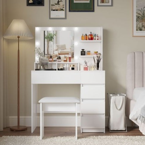 A white makeup vanity desk set with a mirror and lights, featuring multiple storage drawers and a cushioned stool. The vanity is placed in a bedroom setting with various items organized on the mirror's surface.