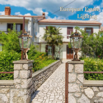 Two decorative outdoor lamps on stone pillars with a residential area in the background.
