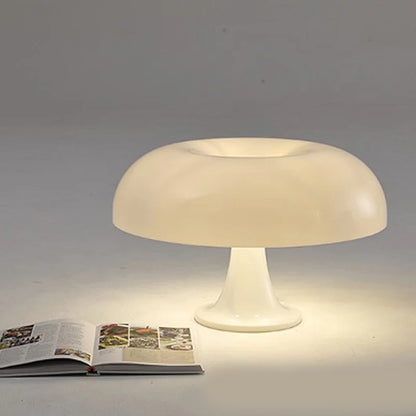 White table lamp on a gray surface with an open book