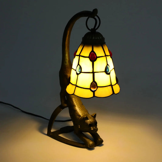 Decorative lamp shaped like a cat with stained glass shade on a dark background
