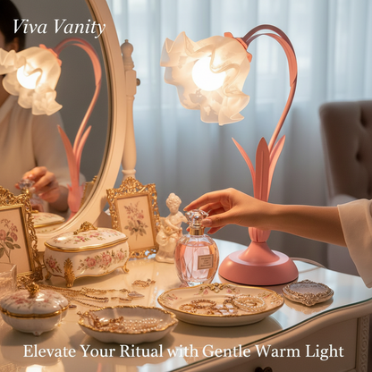 Pink desk lamp with floral design on a white surface next to a vase with flowers.