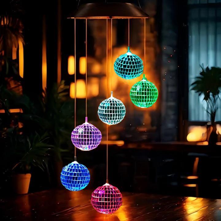 Colorful disco ball wind chime on a wooden floor with blurred indoor background