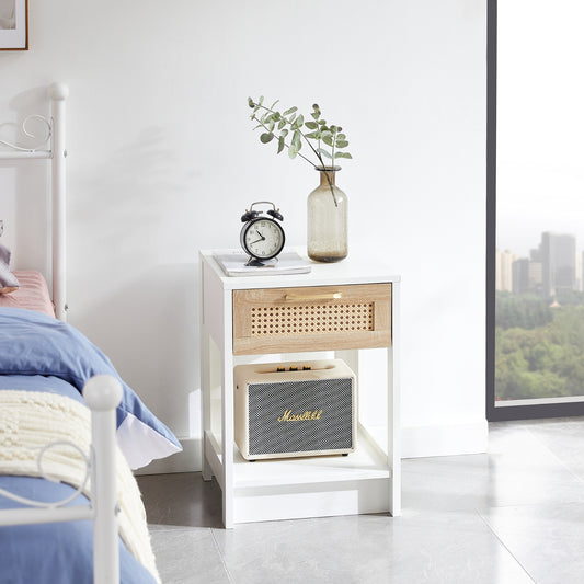 White nightstand with rattan drawer and Marshall speaker next to a bed in a bedroom.
