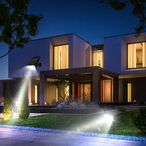 Modern house exterior at night with illuminated windows and garden lights.