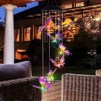 Butterfly-shaped wind chime with colorful lights in a garden setting at night.