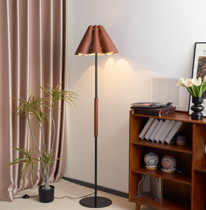 Floor lamp with a brown shade in a room with a bookshelf and plant.