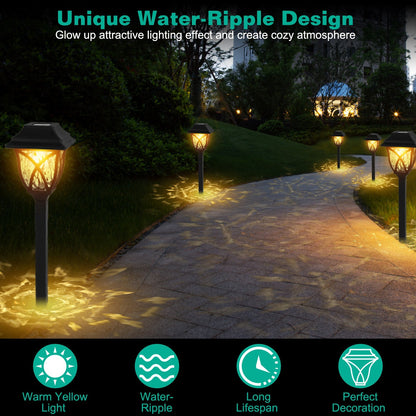 Outdoor pathway with solar lights creating a water-ripple design and warm yellow light.