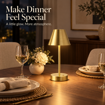 Warm brass table lamp lighting a dining table set for two with linen napkins and flowers.