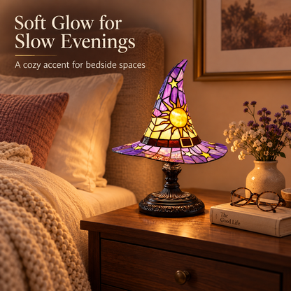 Witch hat accent lamp glowing on a walnut bedside table beside cream bedding