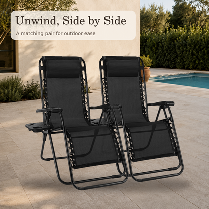 Two black zero gravity patio recliners in a warm poolside setting