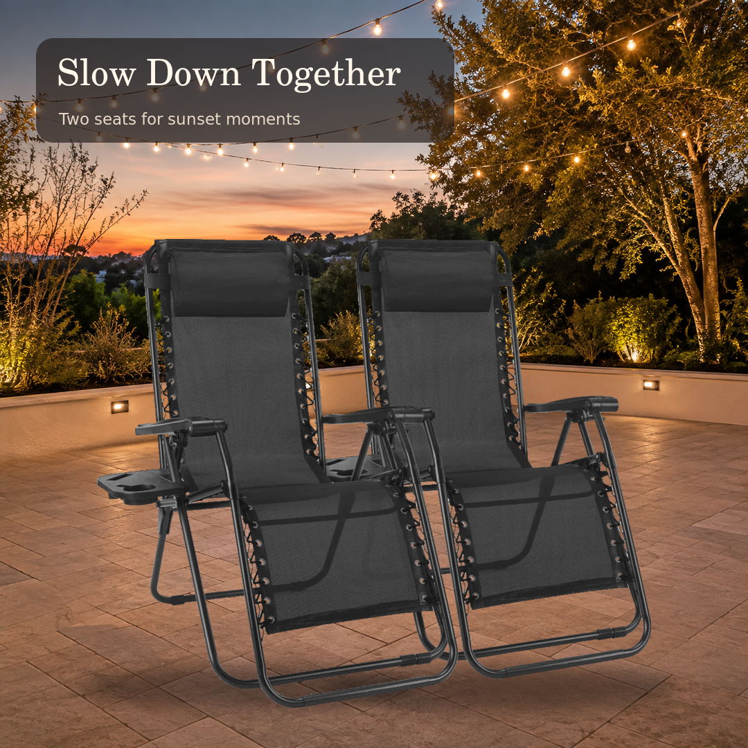 Two black lounge chairs arranged on an outdoor terrace at sunset
